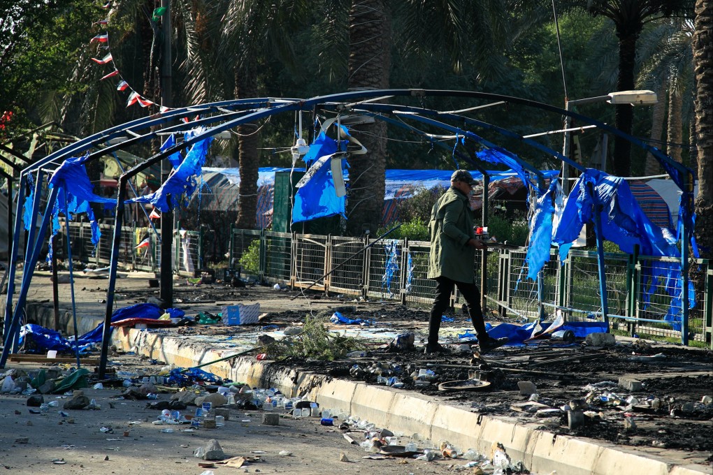 A man walks around burned tents outside the heavily fortified Green Zone in Baghdad, Iraq on Saturday. Photo: AP