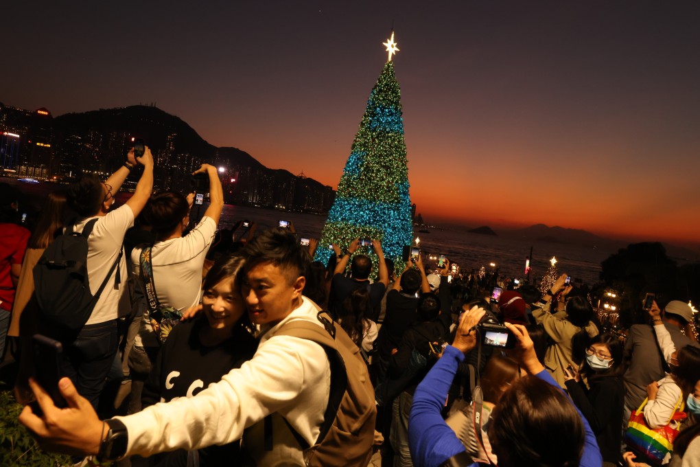 Hong Kong residents take photos of Christmas decorations at the waterfront promenade in West Kowloon Cultural District. The Hospital Authority has advised people to get vaccinated against the seasonal flu as the weather turns cooler. Photo: Nora Tam