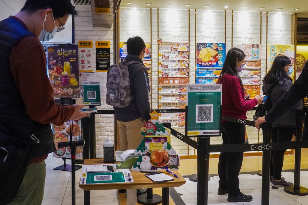 People use the ‘Leave Home Safe’ contact-tracing app to enter a restaurant in Admiralty. Hong Kong authorities are considering a proposal to introduce vaccine passports and ban unvaccinated people from venues such as restaurants. Photo: Sam Tsang