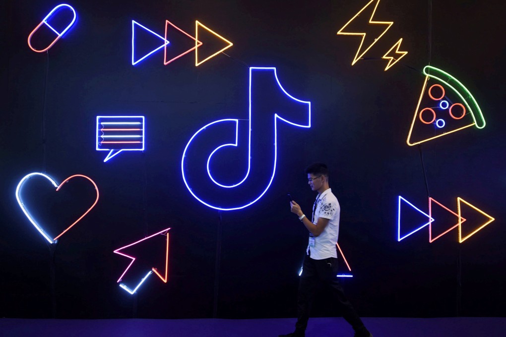A man holding a phone walks past a sign with the logo of Douyin and TikTok at the International Artificial Products Expo in Hangzhou, Zhejiang province, on October 18, 2019. ByteDance, the owner of the platforms, has been testing paid short dramas on Douyin as it searches for new sources of revenue. Photo: Reuters