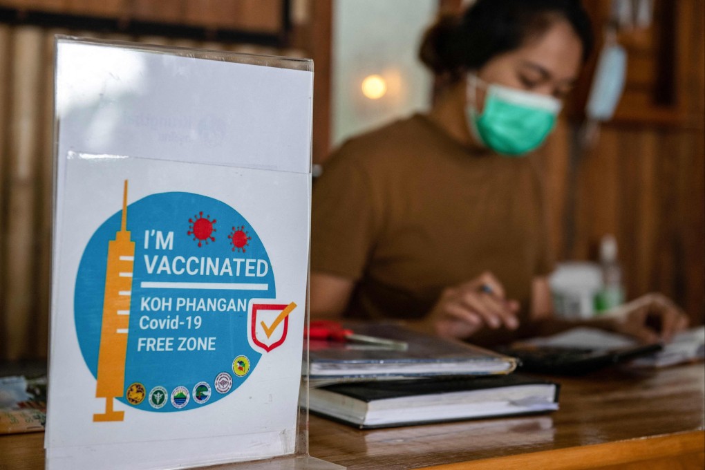 A hotel staff member sits next to a Covid-19 vaccination notice on Koh Phangan in the Gulf of Thailand on November 28. Thailand was one of the first countries to reopen its borders to international travellers. Photo: AFP