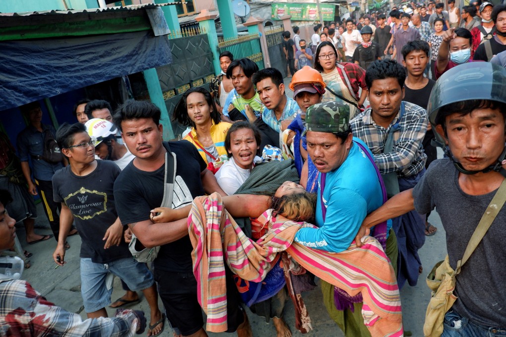 Myanmar anti-coup demonstrators carry an injured protester who was shot during a security force crackdown in March. Photo: Reuters