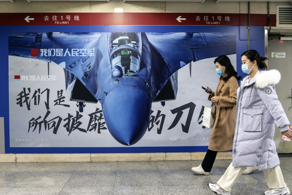Commuters walk past an advertisement promoting the People’s Liberation Army (PLA) Air Force at a subway station in Beijing, China on November 22. Photo: Bloomberg