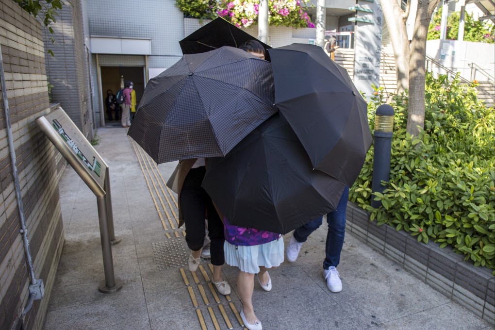 Teacher Lau Kit-yee, wearing a blue skirt, is shielded from photographers as she leaves court following her acquittal. Photo: Brian Wong