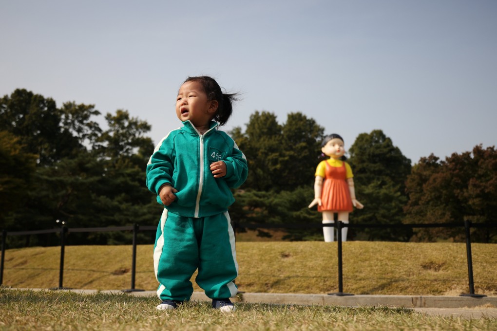 A girl wearing a costume inspired by the Netflix series Squid Game poses in front of a giant doll named Younghee from the series on display at a park in Seoul on October 26. The series, which captures the country’s gaping inequalities and rising household indebtedness, has become an international sensation. Photo: Reuters