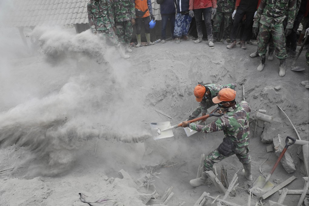 Soldiers search a house buried under volcanic ash from  Mount Semeru eruption. Photo: AP
