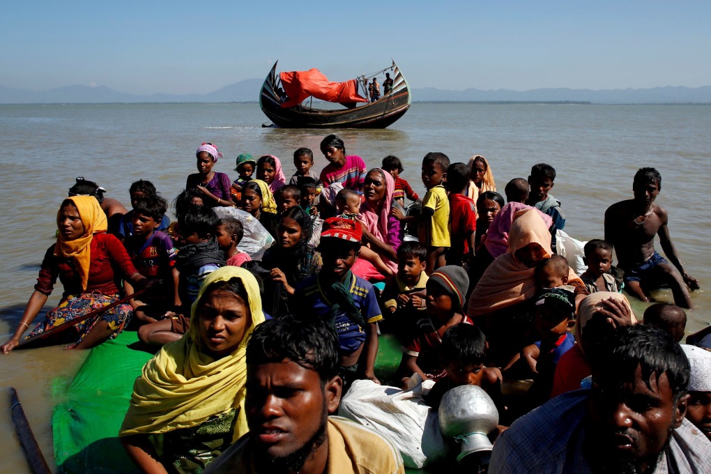 Rohingya refugees sit on a makeshift boat as they are interrogated after crossing into Bangladesh. Photo: Reuters