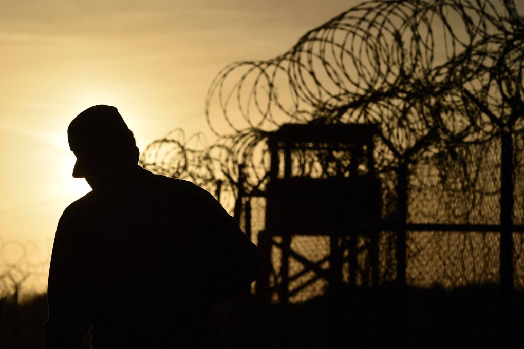 A US soldier walks next to the razor wire-topped fence at Guantanamo Bay, Cuba. Photo: AFP