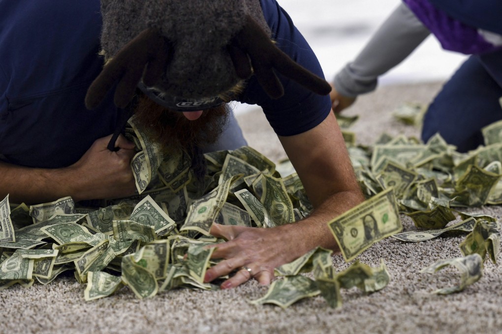 Memorial Middle School teacher Patrick Heyen shovels dollar bills into his shirt at a Dash for Cash event in Sioux Falls on Saturday. Photo: The Argus Leader via AP
