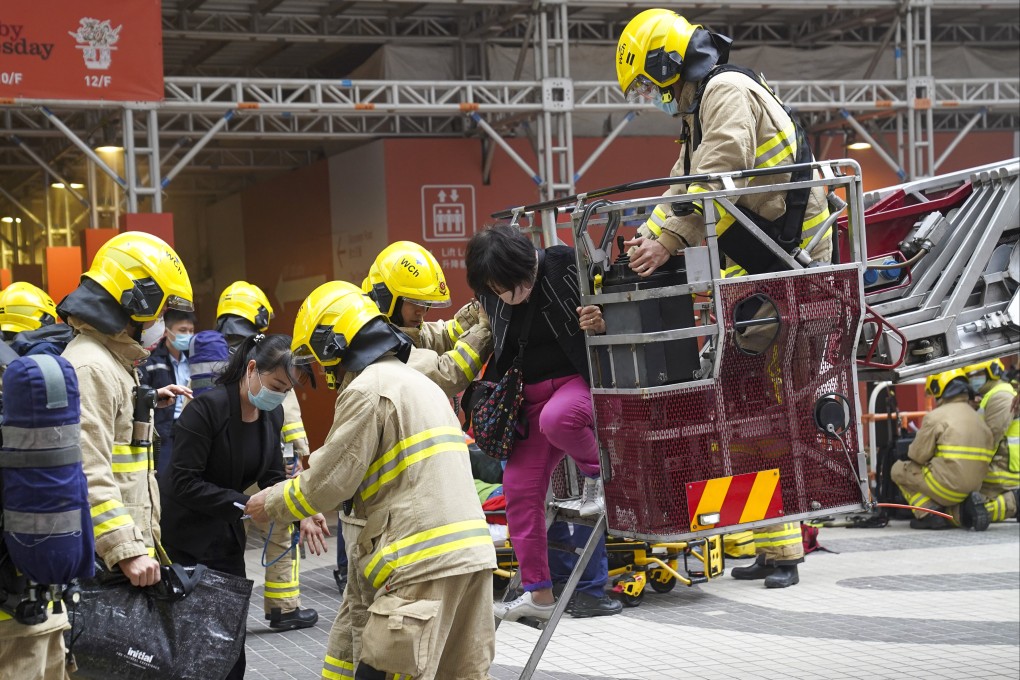 Firefighters help people to safety after the World Trade Centre in Causeway Bay caught fire on Wednesday. Photo: Sam Tsang