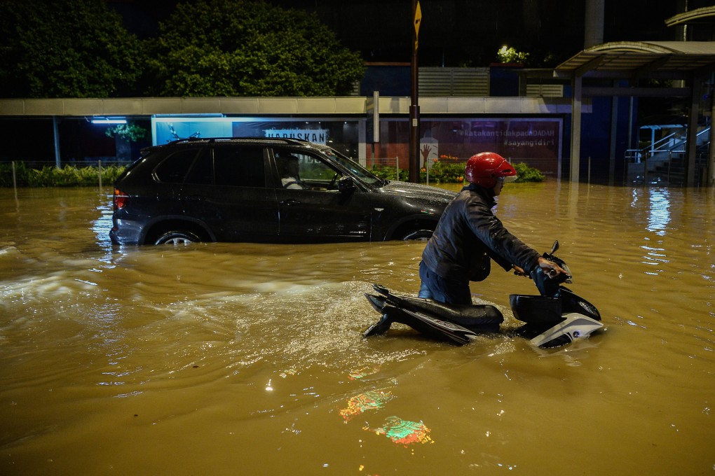 A motorcyclist crosses a flooded street after heavy rains in Kuala Lumpur. Photo: DPA