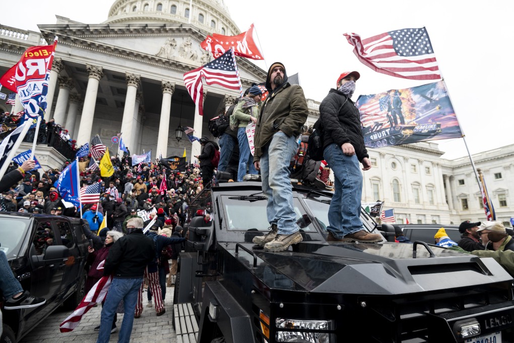Trump supporters stand on a US Capitol Police vehicle as others take over the steps of the Capitol on January 6. Photo: Getty Images