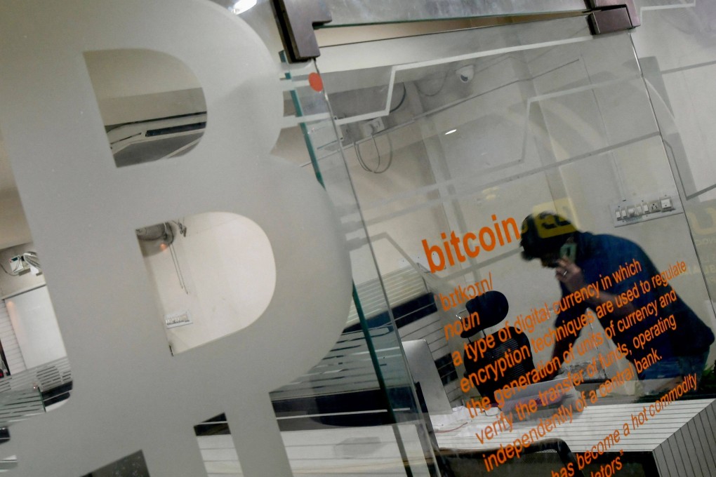 A worker talks on his phone behind a glass partition displaying a bitcoin symbol in an office in Bangalore on November 23. Photo: AFP