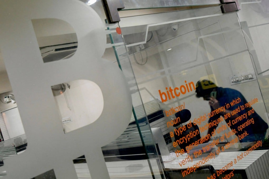 A worker talks on his phone behind a glass partition displaying a bitcoin symbol in an office in Bangalore on November 23. Photo: AFP