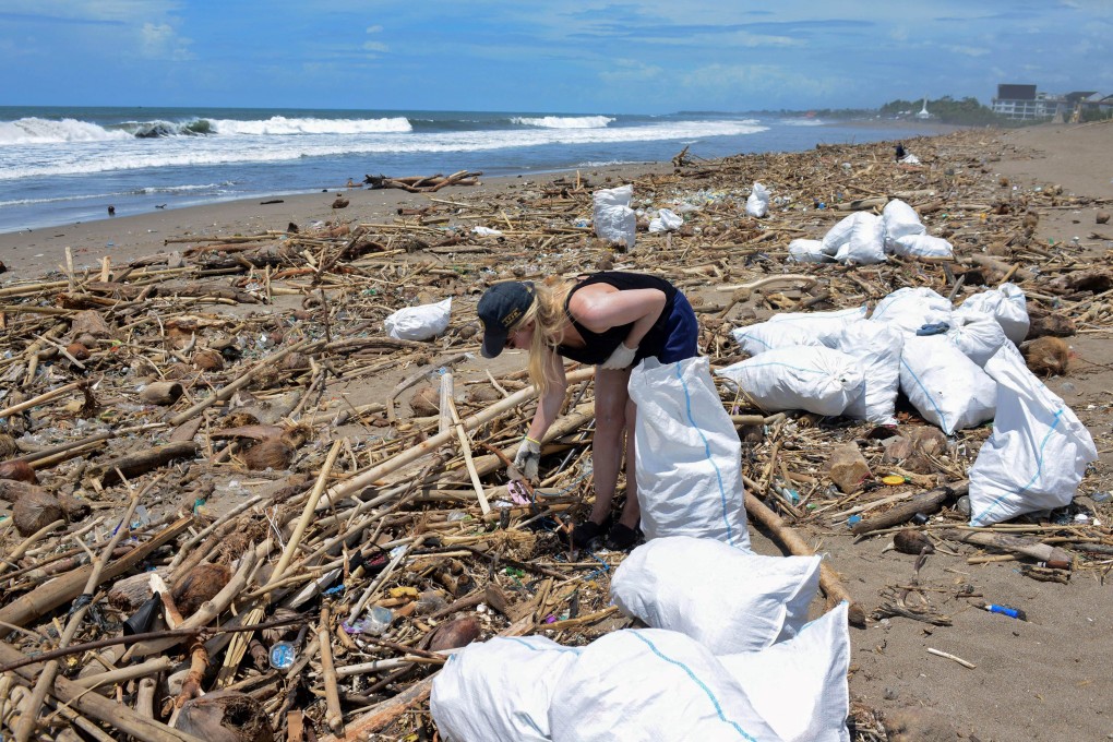 A foreign tourist collects rubbish among piles of debris on Batu Belig beach in Bali after it washed up following an offshore storm. Photo: AFP