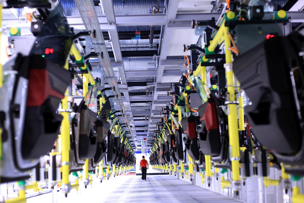 An employee walks between racks holding doors for all-electric Porsche Taycan luxury automobiles at the Porsche AG factory in Stuttgart, Germany. Photo: Bloomberg