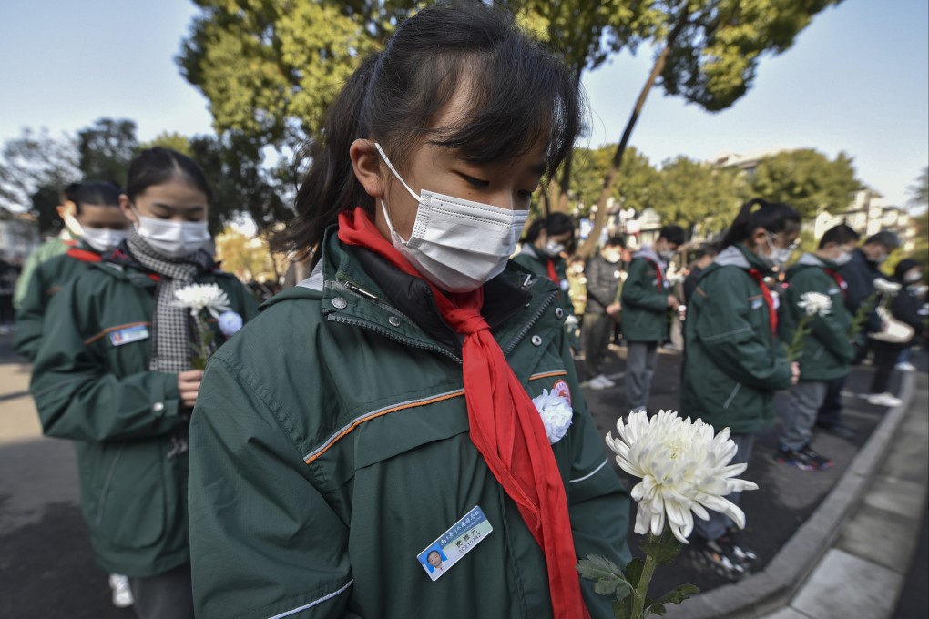 Students holding flowers mourn for the victims of the Nanking Massacre at a mass burial site in Nanjing, Jiangsu province, on December 13, at an event marking the 84th anniversary of the massacre. Photo: Chinatopix via AP