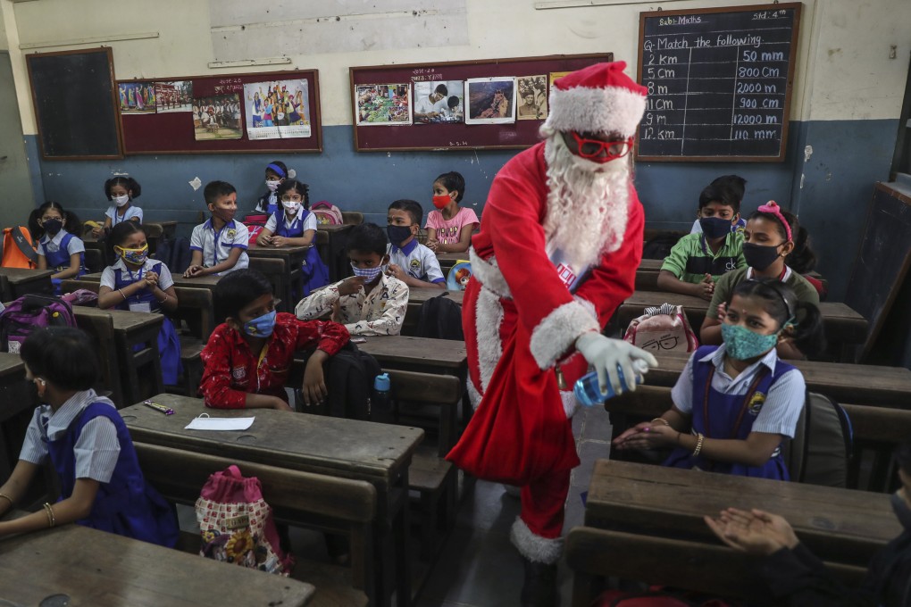 A man dressed as Santa Claus offers hand sanitiser to pupils at a school in Mumbai, India, on Wednesday. Photo: AP