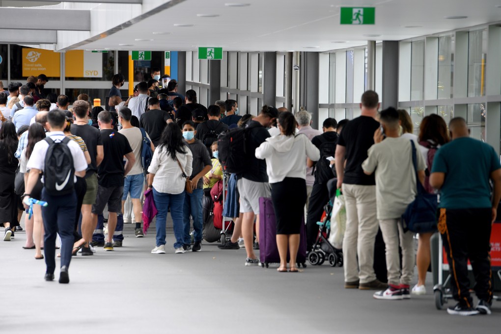 Travellers wait in line for Covid-19 screening outside the departures terminal at Sydney International Airport. At least 80 flights were cancelled on Friday. Photo: EPA-EFE