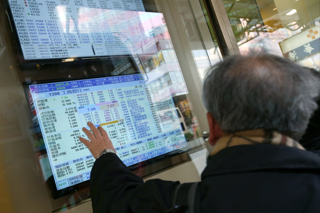 People pointing at an electronic board showing local stock prices in Mong Kok, Hong Kong. Photo: David Wong