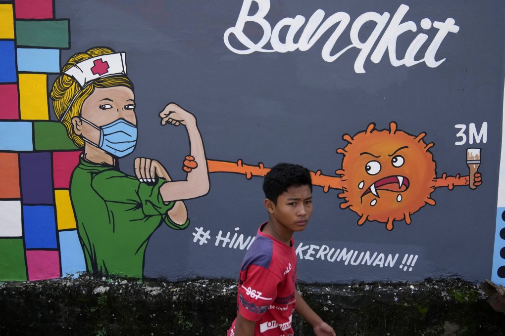A young man walks past a coronavirus-themed mural honouring medical workers in Depok, on the outskirts of Jakarta, Indonesia, on June 25. Although global economic recovery continues, it is uneven, and the Omicron variant has heightened uncertainty. Photo: AP