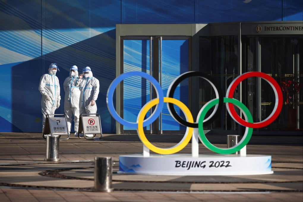 Workers in protective gear stand next to the Olympic rings near the venue for the opening ceremony of the Beijing 2022 Winter Olympics. Photo: Reuters