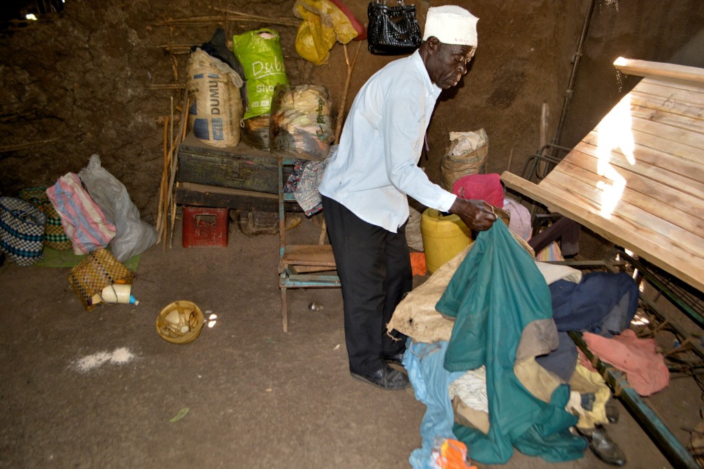 Tito Onyango picks up clothes at the scene where his daughter Mary Atieno was killed after a suspected member of Somali Islamist group Al- Shabaab detonated an explosive device at her village in Kenya last month. Six more people, all men, were reportedly murdered by the group on January 3. Photo: Reuters