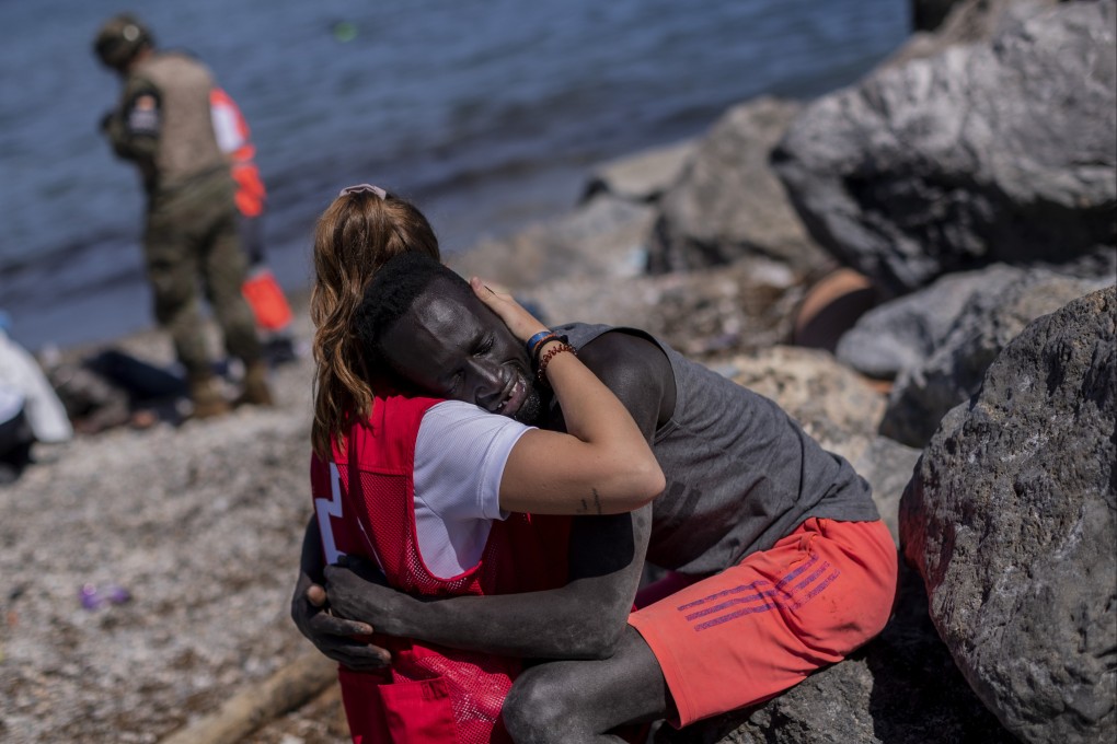 A migrant is comforted by a member of the Spanish Red Cross at the Spanish enclave of Ceuta near the border of Morocco and Spain, in May 2021. Photo: AP