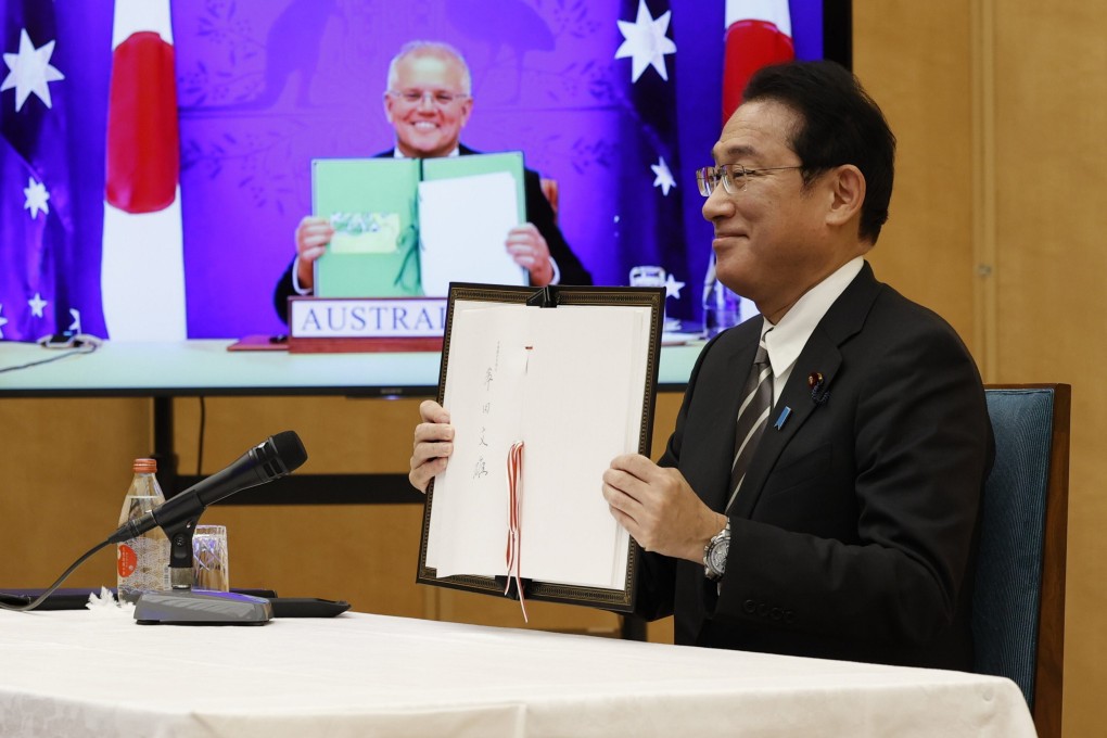 Japan’s PM Fumio Kishida and Australia’s PM Scott Morrison, seen on screen, show off signed documents during a virtual summit to sign the Reciprocal Access Agreement. Photo: AP
