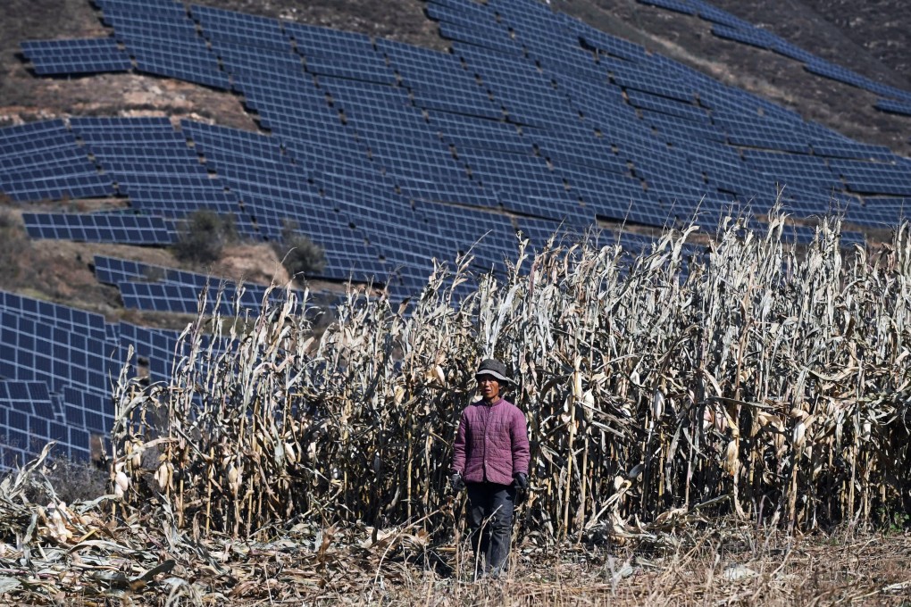 This photo taken on October 23, 2021 shows a farmer in a field near solar panels on a hillside at Huangjiao village in Baoding, China’s northern Hebei province. Photo: AFP