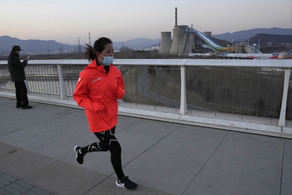 A resident wearing a mask jogs near the Big Air Shougang, a venue for freestyle and snowboard big air events at the Beijing Games. Photo: AP