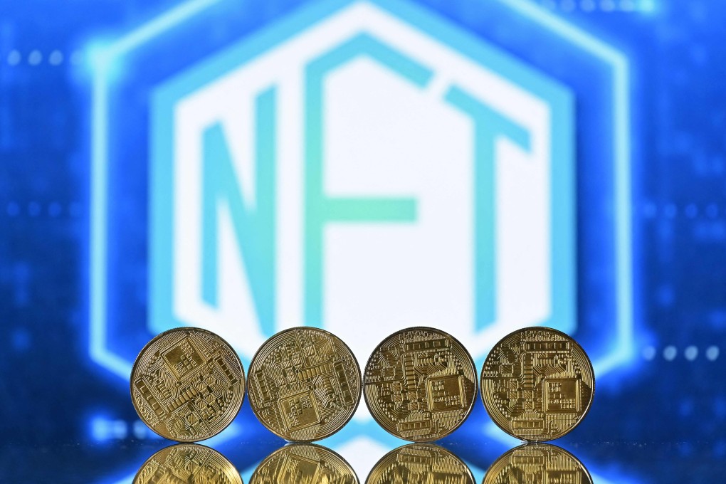 An illustration picture taken in London on December 30, 2021, shows gold plated souvenir cryptocurrency coins arranged by a screen displaying an NFT logo. Photo:  AFP