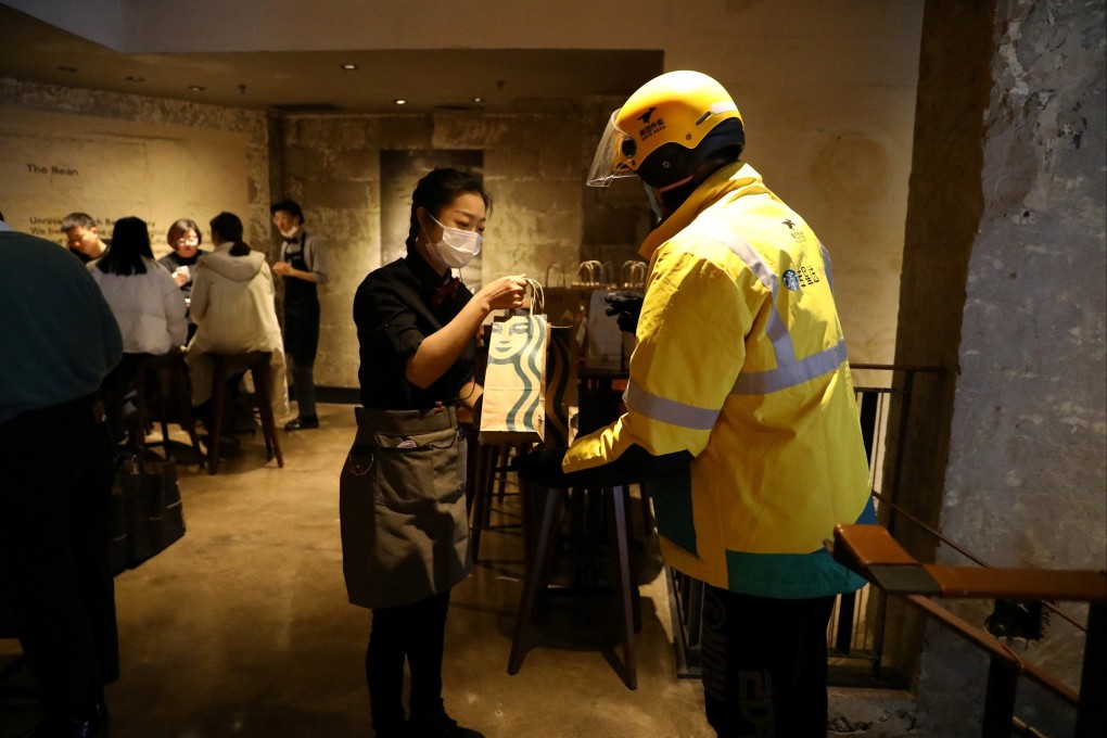 A Starbucks employee hands a bag of ordered food to a Meituan delivery rider at the US coffeehouse chain’s flagship store in Beijing on January 18, 2022. Photo: Reuters