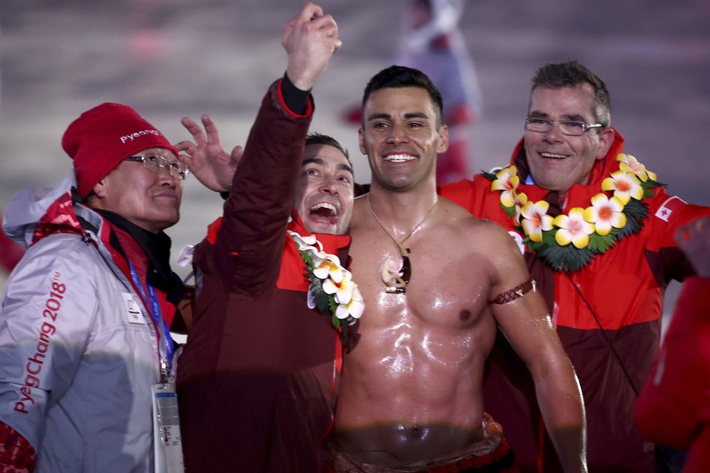 Tonga flag bearer Pita Taufatofua poses with a volunteer and teammates during the opening ceremony of the 2018 Winter Olympics in South Korea. Photo: AP