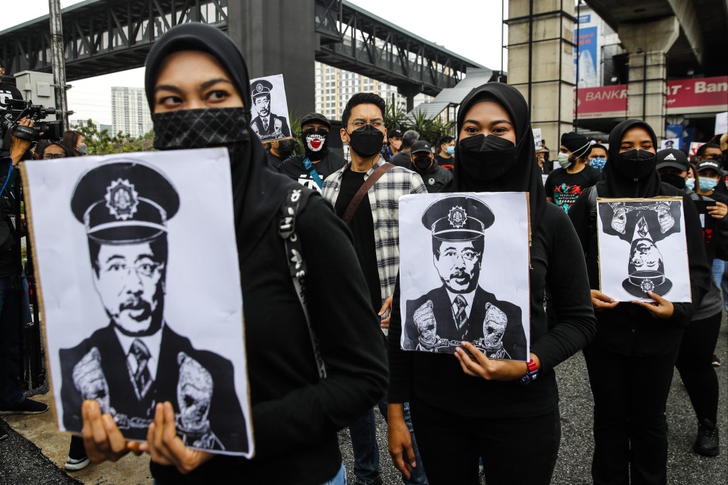 Protesters hold placards displaying the face of Azam Baki. Photo: EPA