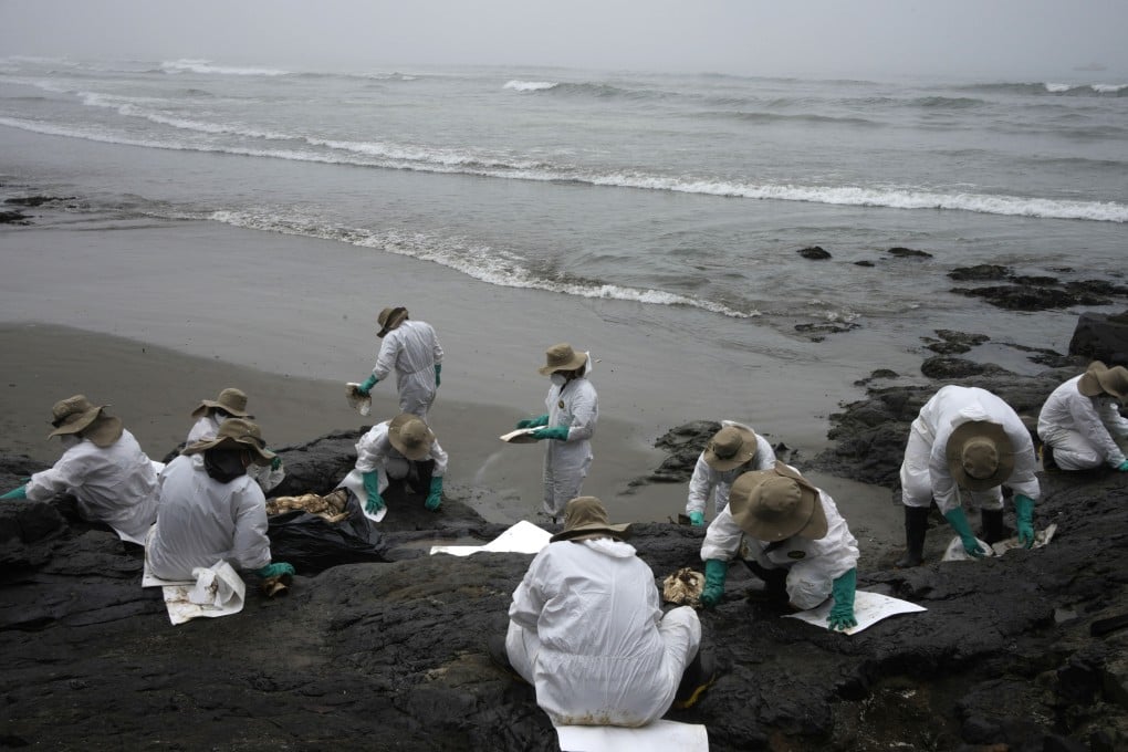 Workers clean oil on Cavero Beach in the Ventanilla district of Callao, Peru on January 22. Photo: AP