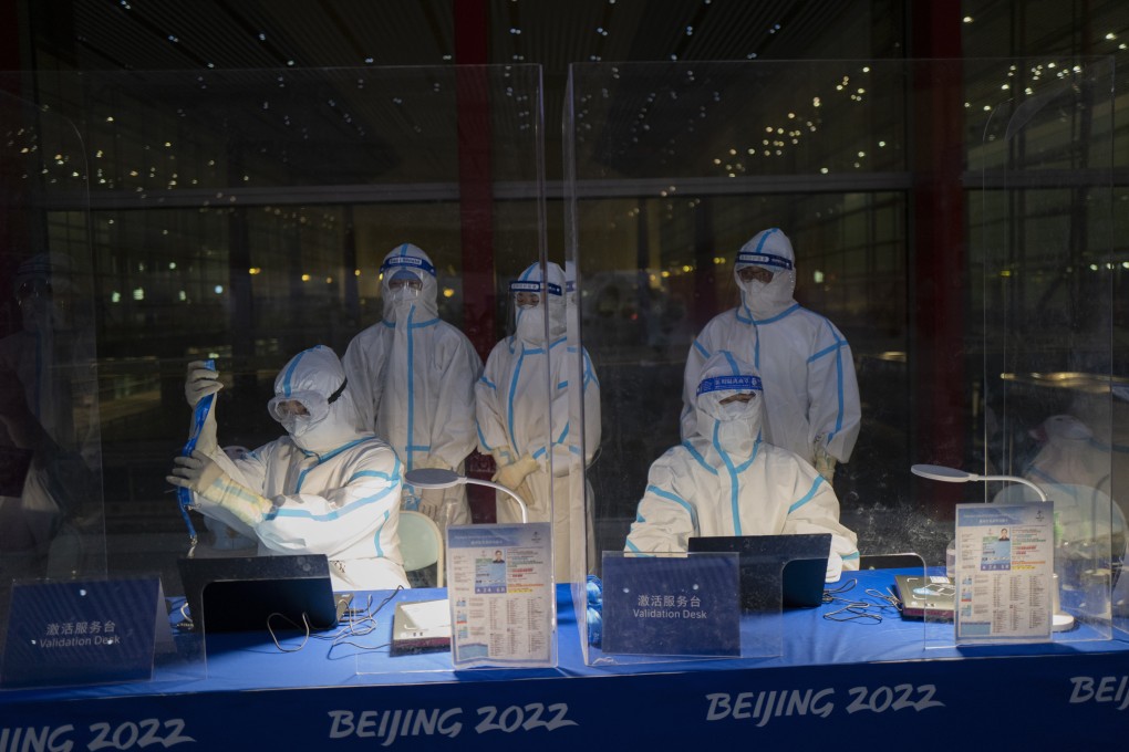 Workers in protective gear at the Beijing Capital International Airport wait to inspect Olympic credentials ahead of the Winter Games. Photo: AP
