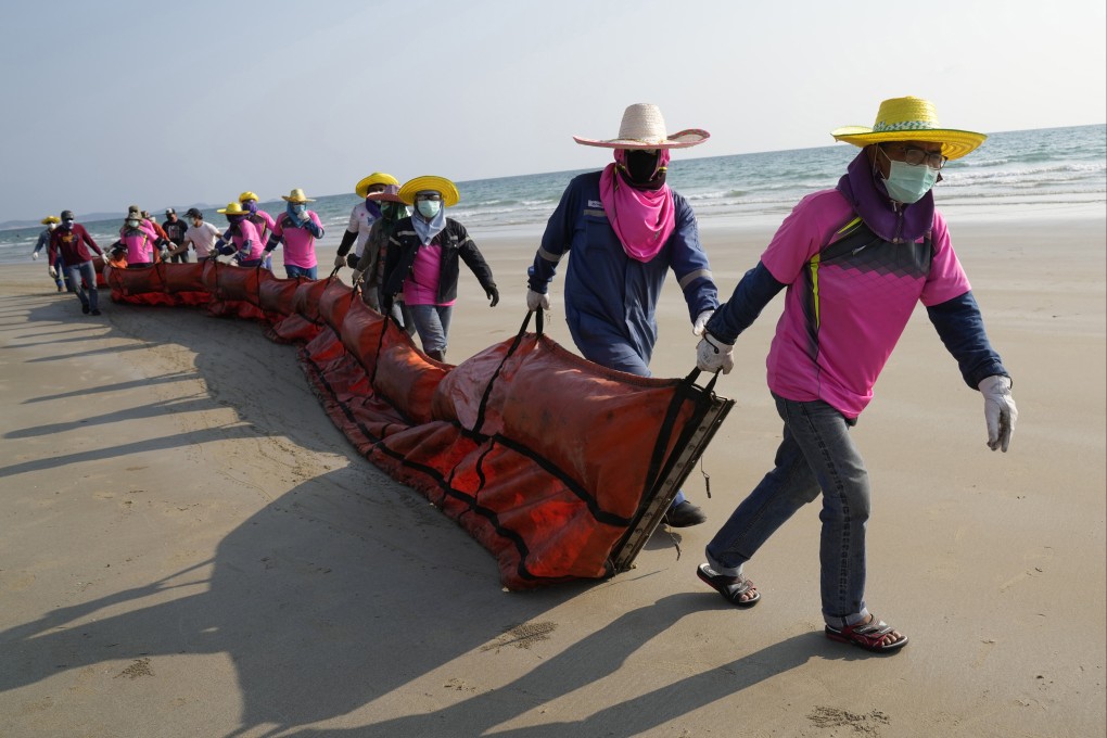 Workers in Thailand drag an oil spill boom out onto Mae Ram Phueng Beach on Friday in the hope of containing any oil that washes ashore from a spill at sea. Oil slicks were approaching beaches on the east coast, home to fragile coral and seagrass, officials said. Photo: AP