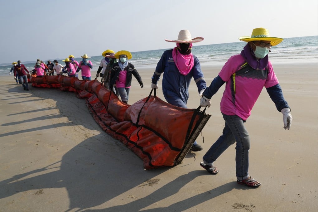 Workers in Thailand drag an oil spill boom out onto Mae Ram Phueng Beach on Friday in the hope of containing any oil that washes ashore from a spill at sea. Oil slicks were approaching beaches on the east coast, home to fragile coral and seagrass, officials said. Photo: AP
