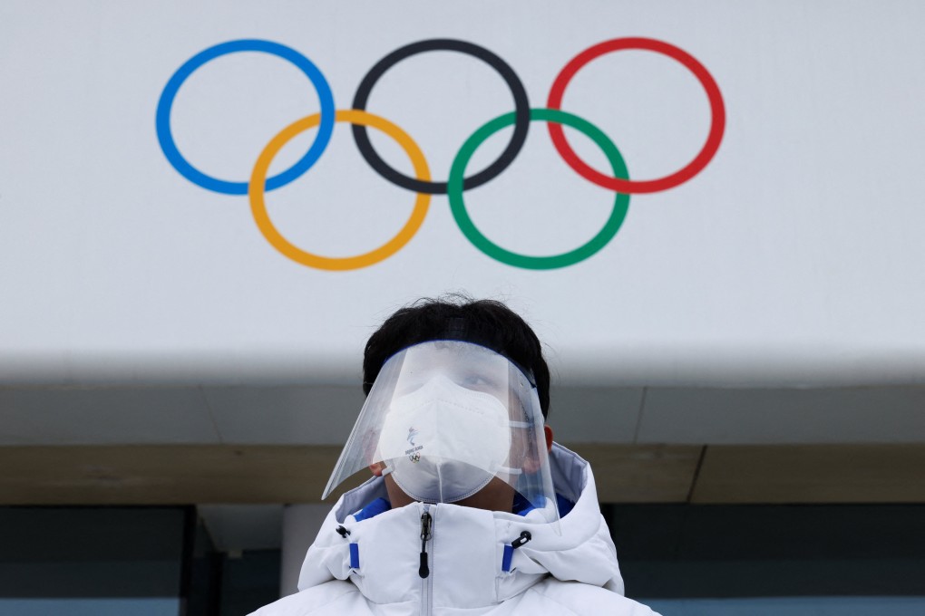 A volunteer stands in front of Olympics Rings at the National Aquatics Centre in Beijing. Photo: Reuters
