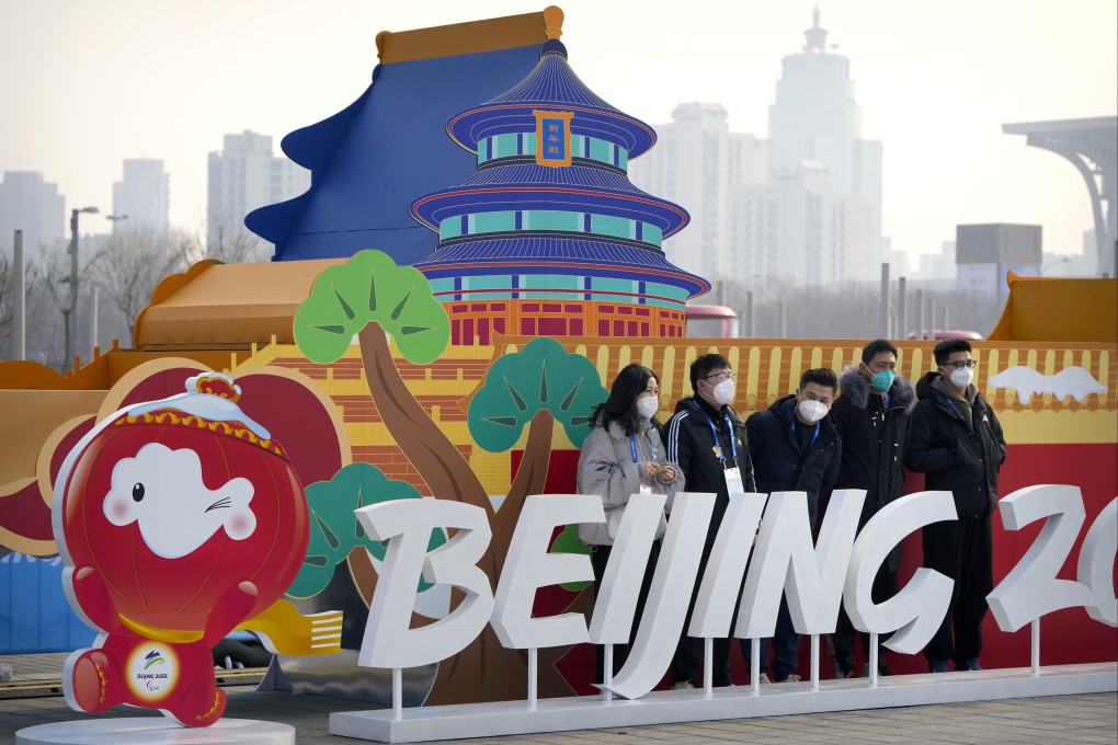 Staff members pose for a group photo with a Beijing 2022 Olympics display on the Olympic Green near the main media centre. Photo: AP
