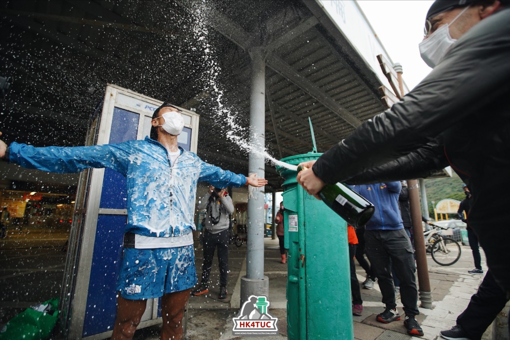 Wong Ho Chung is sprayed with champagne next to the green postbox at Mui Wo pier, the finish line for the Hong Kong 4 Trails Ultra Challenge. Photo: Vincent Chan