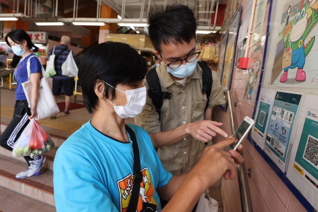 Social worker Michael Fung Siu-pan, who works with St James’ Settlement, teaches Wai, who has been a street sleeper for four years, to use the LeaveHomeSafe app on a smartphone donated through the charity, on November 1, 2021. Photo: Nora Tam