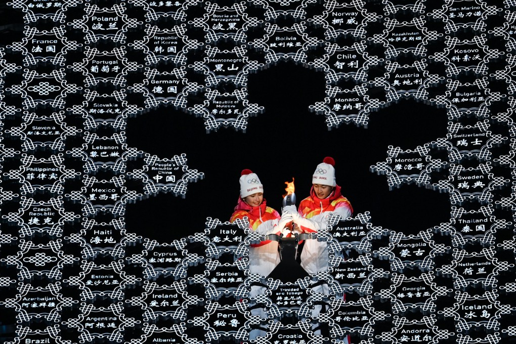 Torch bearers Dinigeer Yilamujiang (left) and Zhao Jiawen set the torch into the Olympic cauldron. Photo: Xinhua