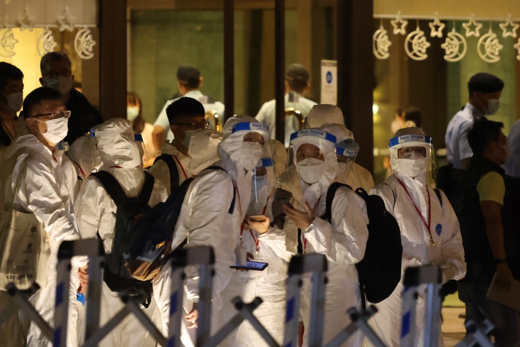 Police and health workers wearing personal protective equipment are seen at a residential tower in Hong Kong under coronavirus lockdown last summer. Photo: K. Y. Cheng