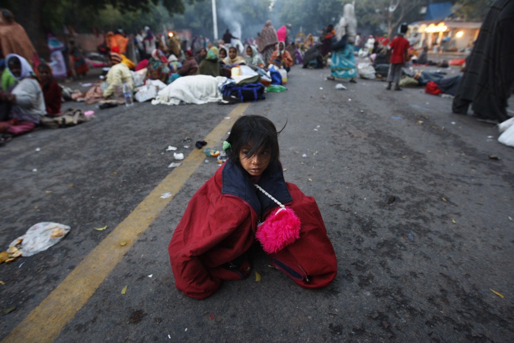 A child near the Indian Parliament, in New Delhi, takes shelter from the wind as protesters arrive in the capital for protests against rising inflation and unemployment. Photo: AP