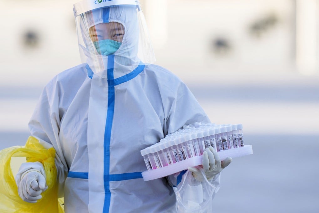 An official in protective gear carries Covid-19 PCR test kits at the Winter Olympics village in Beijing. Photo: Kyodo