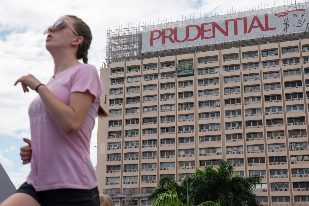A woman runs past a banner featuring the Prudential logo on a building in Hong Kong. Photo: Bloomberg