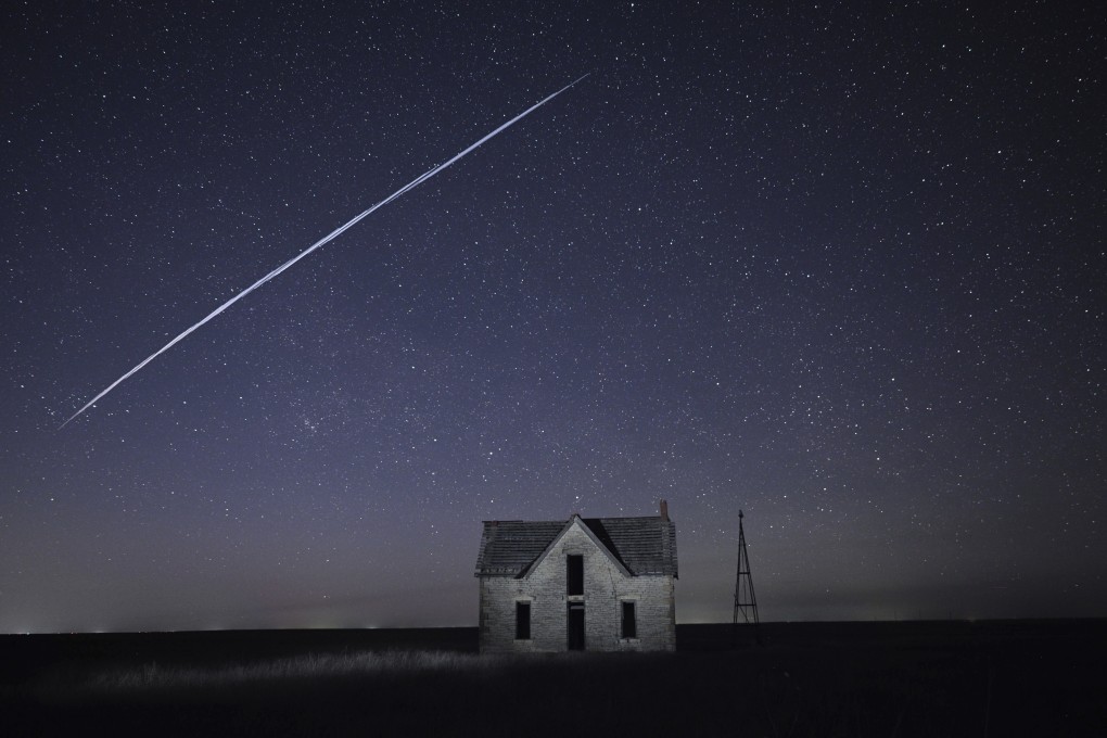 A long exposure image shows a string of SpaceX Starlink satellites passing over an old stone house near Florence, Kansas, in May 2021. Photo: AP