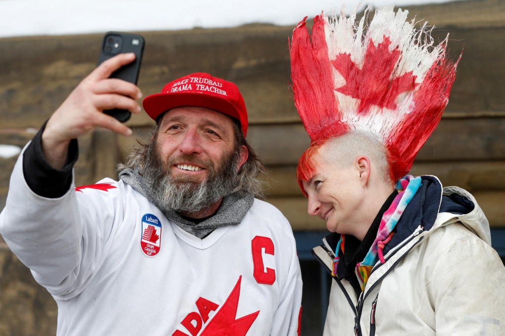 A man in a “Make Trudeau a drama teacher again” cap takes a selfie with a woman whose mohawk is painted with a Canadian maple leaf design, as truckers and supporters continue to protest against vaccine mandates, in Ottawa. Photo: Reuters